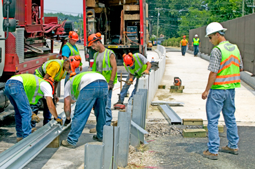 Men hard at work on the construction ofa guard rail.